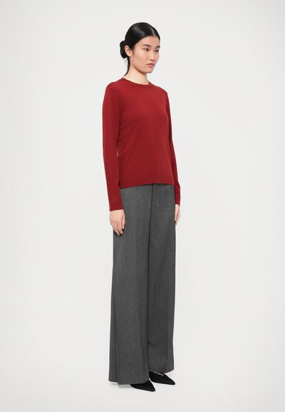 Red long-sleeve sweater paired with grey wide-leg trousers. The sweater has a round neckline; the trousers feature a subtle texture. Black pointed shoes.