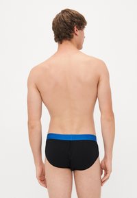 Zwarte boxershorts met een blauwe tailleband, gemaakt van een gladde stof. De achterkant toont een aansluitend ontwerp en minimale naden.