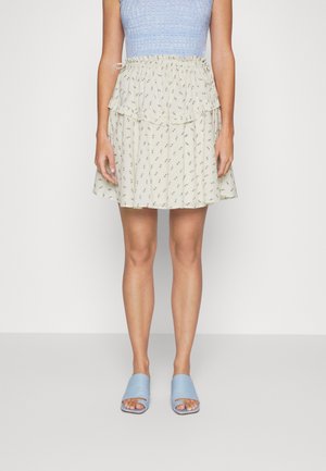 Falda beige claro con una capa rizada y un patrón floral. Acompañada de sandalias deslizables azules. Top azul texturizado con un diseño ajustado.