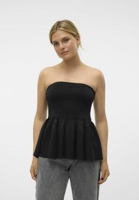 Svart strapless peplumtop med en åtsittande byst och utsvängd volangkant. Slät stretchig tyg, kombinerad med högmidjade grå jeans.