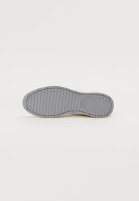 Grå gummi yttersåle med lineært deksemønster, som har subtil merkevare. Rent design med en jevn tekstur og nøytral farge.