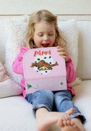 Różowe pudełko z postacią o pomarańczowych włosach i kropki, oznaczone napisem „PIPPI”. Dziecko trzyma je, ubrane w różową koszulkę i niebieskie dżinsy.