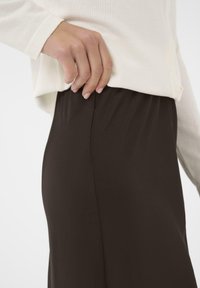 Bruine rok met een soepele textuur, slim fit en een elastieken tailleband, gecombineerd met een crèmekleurige, lichtgewicht, geknoopte trui.
