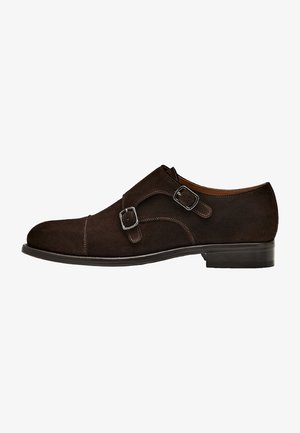 Brązowe zamszowe buty monk strap z podwójnymi klamrami, elegancka zaokrąglona czubek i płaska skórzana podeszwa. Minimalne detale przeszyć.