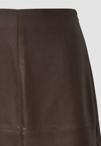 Jupe en cuir marron avec une surface texturée, des coutures verticales et un design épuré. La coupe est droite et ajustée à la taille.