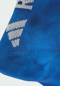 Calzino blu con un punto lavorato a maglia. Il design include un logo bianco e un distintivo motivo diagonale integrato nel tessuto.