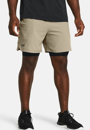 Pantalones cortos deportivos beige con un diseño ligero, que presentan un logo lateral y se combinan con mallas compresoras negras y zapatos negros.