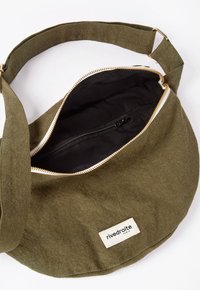 Sac en tissu vert olive avec une forme courbée, fermeture éclair dorée et doublure intérieure noire. Présente une étiquette avec le logo "rive droite".