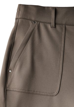 Brown fabric pants featuring a large angled pocket, subtle texture, and contrasting stitching along the edges. Metal snap fastener visible.