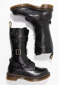 Bottes noires à la cheville en cuir lisse, dotées de plusieurs sangles réglables, d'une fermeture éclair latérale et d'un détail de surpiqûres orange contrastantes.