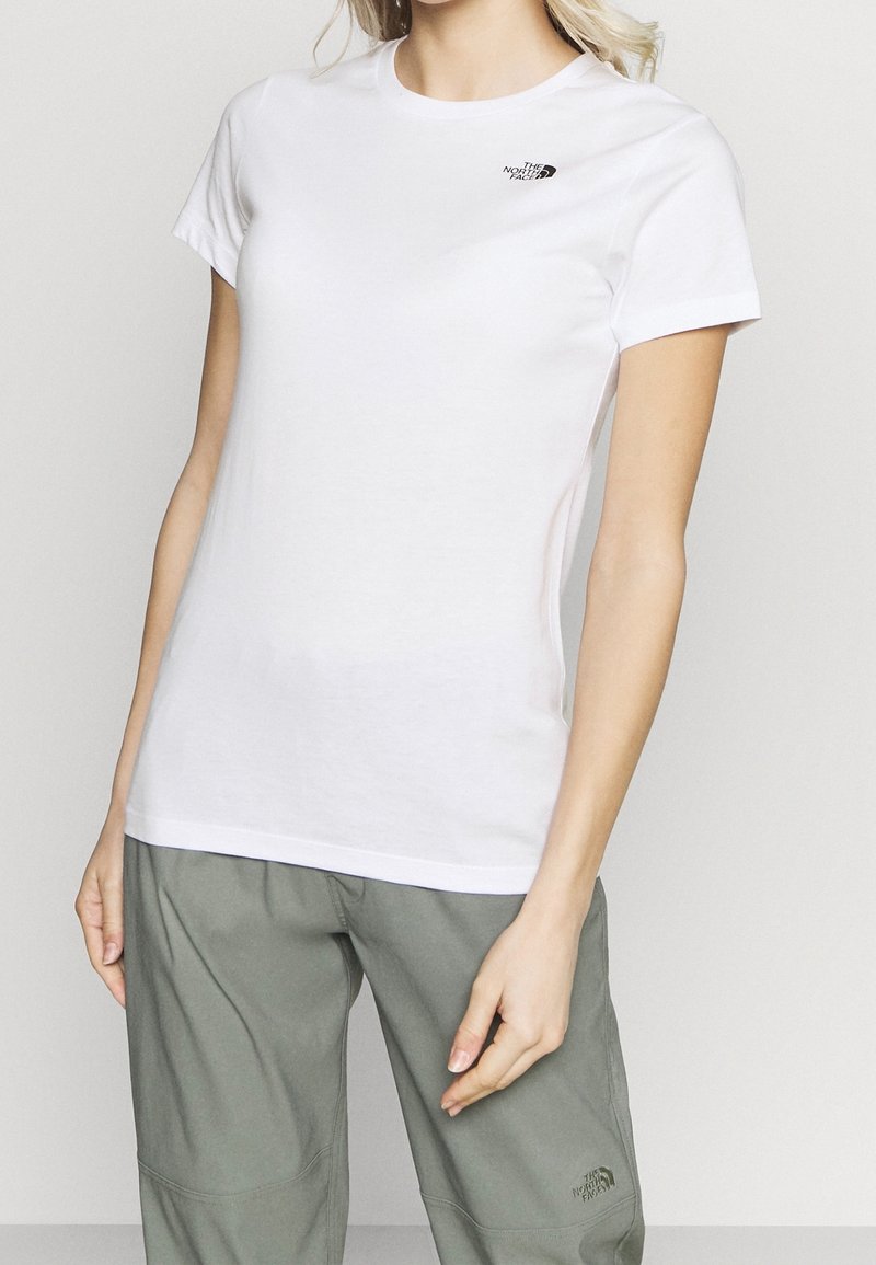 Vit bomull t-shirt med korta ärmar, med en liten svart logotyp på vänster bröst. Slät textur, rundad halsringning, figursydd design.