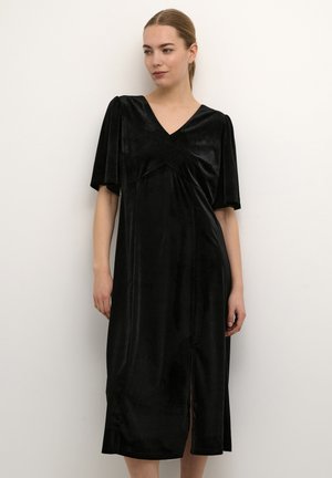 Robe en velours noir à manches courtes et décolleté en V, avec une fente à l'avant et un design drapé. Texture lisse et longueur midi.