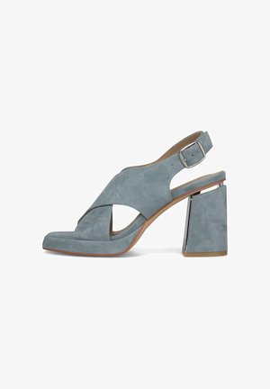 Lichtblauwe suède open-teen slingback sandaal met brede blokhak en zilveren gespband.