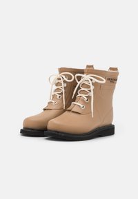 Botas de goma marrones con puntera redonda, cordones en la parte frontal y ojales de metal. Cuentan con una parte superior texturizada y una suela negra resistente.