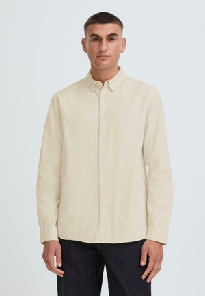Long-sleeve beige shirt made of soft fabric, featuring a button-down collar, front buttons, and subtle embroidery on the chest.