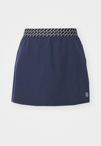 Námořnická modrá sportovní sukně s texturovaným elastickým páskem, který má geometrický vzor. Obsahuje detail loga na spodní části.