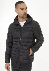 Chaqueta de plumón negra con capucha, con cierre de cremallera, diseño acolchado horizontal, dos bolsillos frontales y una textura suave.
