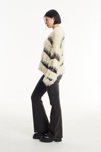 Ψεύτικη γούνα σε κρέμα χρώμα με μαύρες ρίγες, φαρδιά σκούρα τζιν και χοντρές μαύρες πλατφόρμες. Διαθέτει χνουδωτή υφή και φαρδιά εφαρμογή.