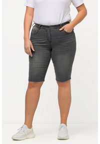 Shorts en denim gris au design ajusté, taille élastique, poches frontales et finition ourlée. Associés à des baskets blanches et un t-shirt blanc.
