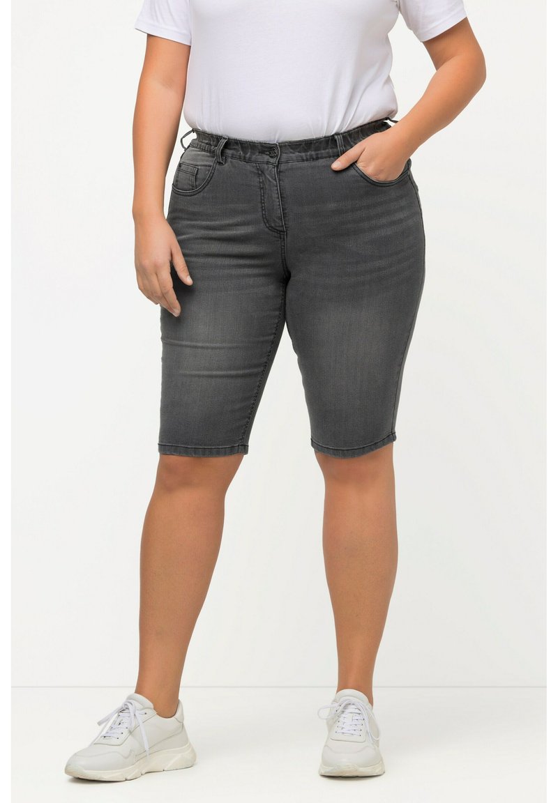 Shorts en denim gris au design ajusté, taille élastique, poches frontales et finition ourlée. Associés à des baskets blanches et un t-shirt blanc.