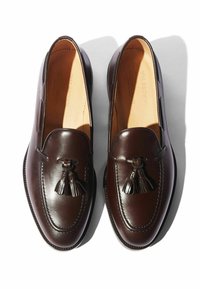 Bruine leren loafers met franje, met een glanzende afwerking, ronde neus en contrasterende stiksels. De zool heeft een lichte glans.