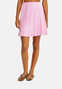 Ružová áčková sukňa vyrobená z ľahkého materiálu, s rozšíreným strihom, ktorý končí nad kolenami. Tkanina má hladký, mierne lesklý povrch.