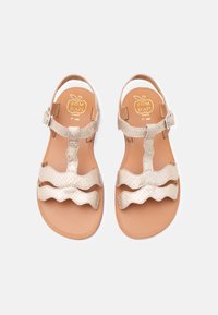 Ζευγάρι μπεζ δερμάτινων σανδαλιών με κυματιστές λουρίδες και αγκράφα στον αστράγαλο σε επίπεδες ταμπά σόλες, με την επωνυμία "POM D'API" με χρυσά γράμματ α.