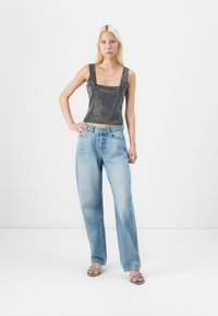Black sleeveless top with square neckline and textured pattern, paired with light blue wide-leg denim jeans. Plain sandals complete the outfit.
