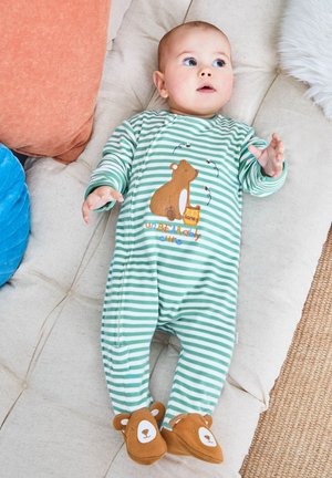 Zielono-biały pajacyk dla niemowląt w paski z motywem misia, tekstem "niesamowicie uroczy" i brązowymi bucikami w kształcie misia. Gładka tekstura materiału.