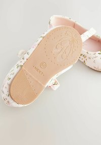 Ballerine bianche con un motivo floreale in rosa e verde. Fodera morbida, suola piatta beige con presa testurizzata e una fascia sopra.
