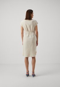 Rochie bej scurtă, cu o croială lejeră, mâneci tip căpăcel, curea la talie și slituri laterale; confecționată dintr-un material ușor, cu un finisaj texturat.