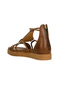 Sandalo in pelle marrone con molteplici cinturini, suola a zeppa bassa e cerniera sul lato. Presenta una texture liscia e un design semplice.