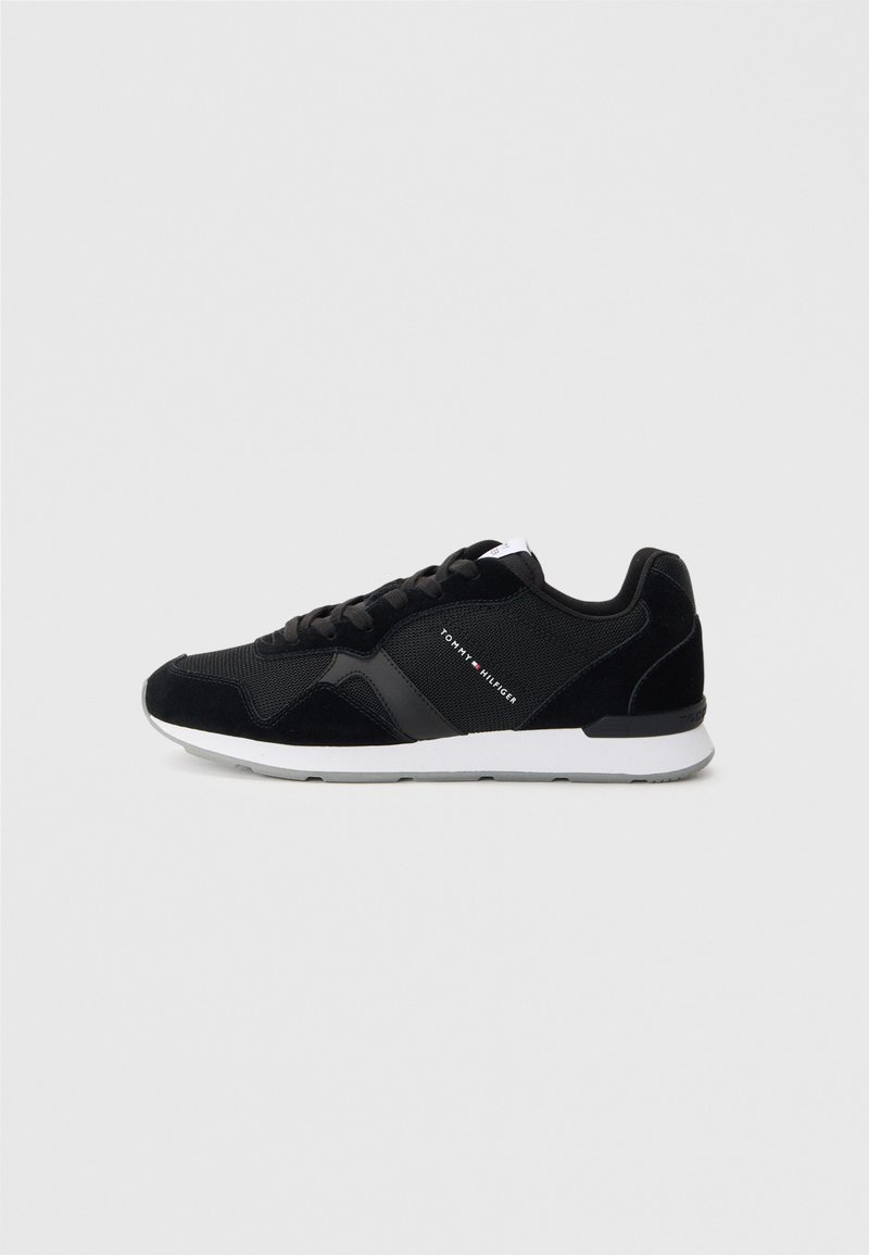 Pantofi sport negri din material mesh și suede, având o talpă intermediară albă și un logo pe lateral. Design cu șireturi și vârf rotunjit.
