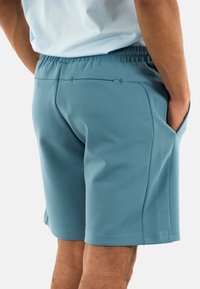 Shorts sportivi blu realizzati in tessuto elastico, con vita elasticizzata, tasche laterali e una tasca posteriore con zip.