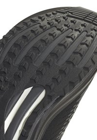 Sola di scarpa sportiva nera con modelli di battistrada profondi e imbottitura bianca visibile vicino al tallone, marchiata Continental per aderenza e durata.