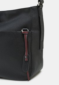 Mustan nahkainen olkalaukku, jossa on teksturoitu pinta, raidallinen vetoketjun nyöri, hopeiset yksityiskohdat ja merkki logo.