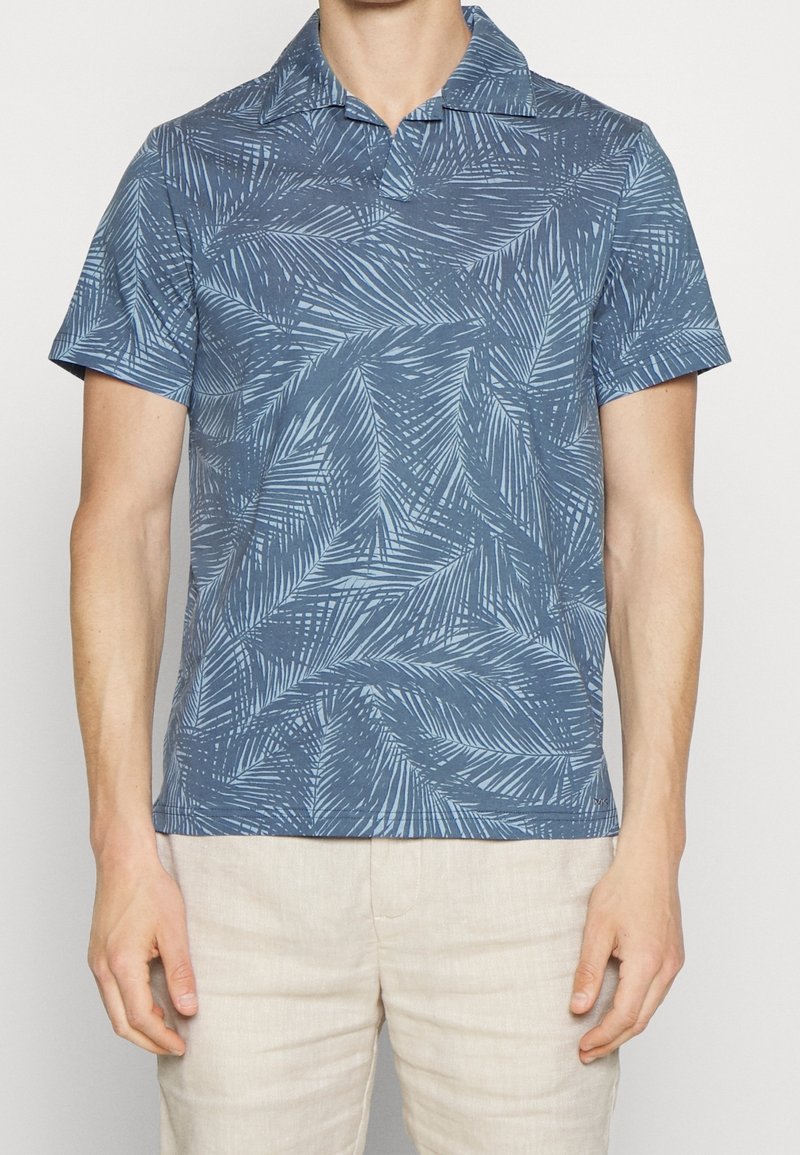 Polo à manches courtes en tissu bleu, avec un motif de feuille texturé. Design avec col et ourlet droit, adapté pour un usage décontracté.