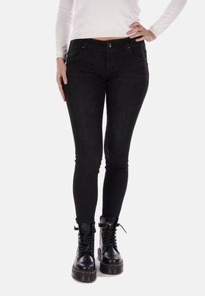Jeans skinny neri con vita alta, cinque tasche e una superficie in denim liscia. Indossati con stivali militari neri con lacci.