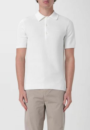Polo shirt bianco a maniche corte in maglia, con colletto classico, pattina con tre bottoni, orlo a coste e un delicato motivo testurizzato.