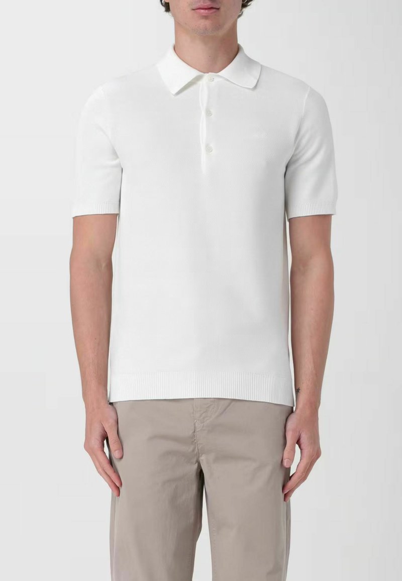 Polo shirt bianco a maniche corte in maglia, con colletto classico, pattina con tre bottoni, orlo a coste e un delicato motivo testurizzato.