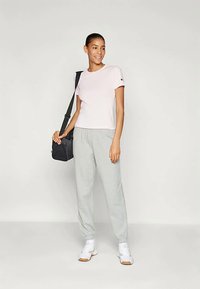 Roosa puuvillane T-särk lühikeste varrukatega, koos heledate hallide dressipükstega. Must õlakott ja valged sportlikud kingad täiendavad riietust.