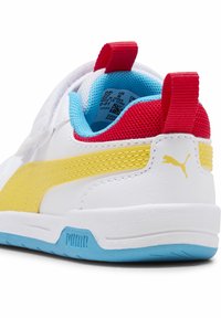 Baskets blanches avec une bande jaune, accents rouges et bleus. Dotées d'un dessus texturé et d'une semelle en caoutchouc avec un motif de traction bleu.