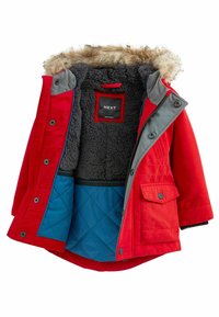 Röd isolerad parka med grå detaljer och fuskpäls-krage. Har en quiltad blå innerfoder, framfickor och dragkedjestängning.