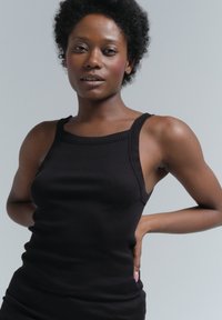Schwarzes geripptes Tanktop mit breiten Schulterträgern und taillierter Silhouette, mit strukturiertem Stoff und Rundhalsausschnitt.