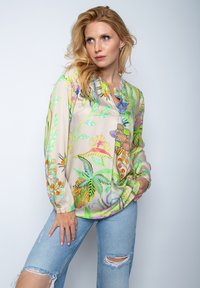 Lichte blouse met lange mouwen in beige, versierd met levendige botanische prints in groen, roze en blauw; heeft een ronde halslijn en een losse pasvorm.