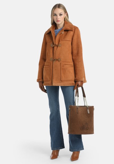 Cappotto in suede marrone con chiusure a toggles, due tasche frontali e colletto morbido. Abbinato a jeans flare in denim scuro e una borsa a secchiello marrone con logo.