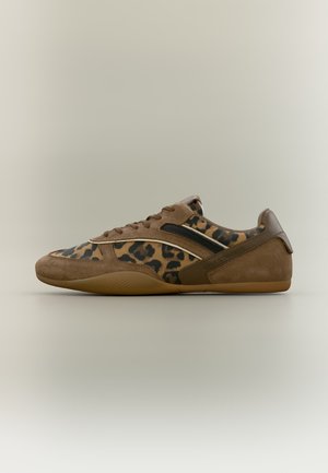 Zapatilla deportiva de ante marrón con paneles de estampado de leopardo, detalle de franja negra y suela de goma, mostrada de perfil sobre fondo neutro.