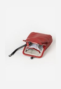 Red leather pouch with black hardware, featuring a striped fabric interior and a black strap, opening at the top with a clasp closure.