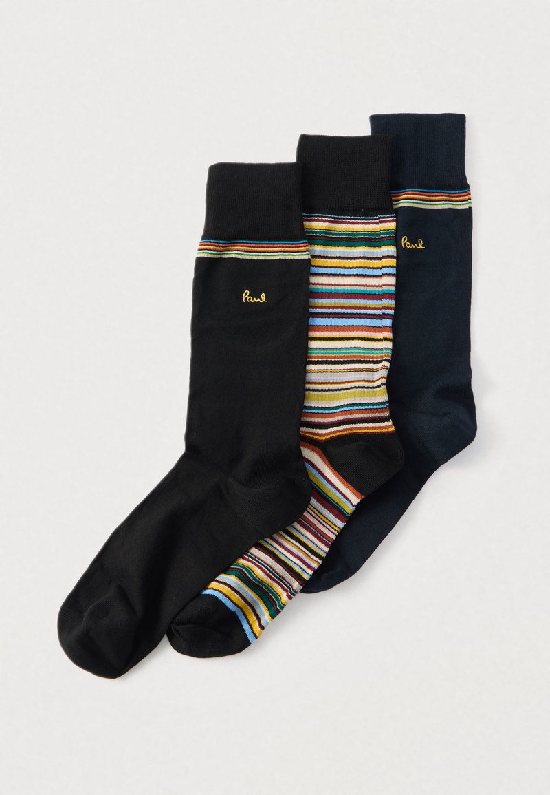 Trois paires de chaussettes : une noire unie, une à rayures multicolores, et une bleu marine unie. Toutes comportent un petit logo doré « Paul ».