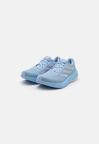 Baskets de sport bleu clair avec une tige en maille texturée, trois bandes blanches sur le côté, un col rembourré et une semelle en caoutchouc pour une meilleure adhérence.